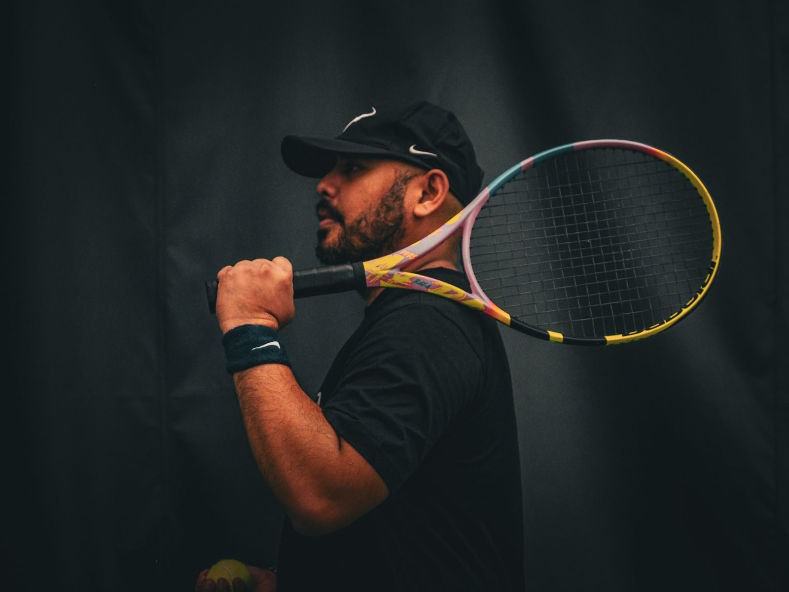 A tennis player resting a racket on his shoulder before training